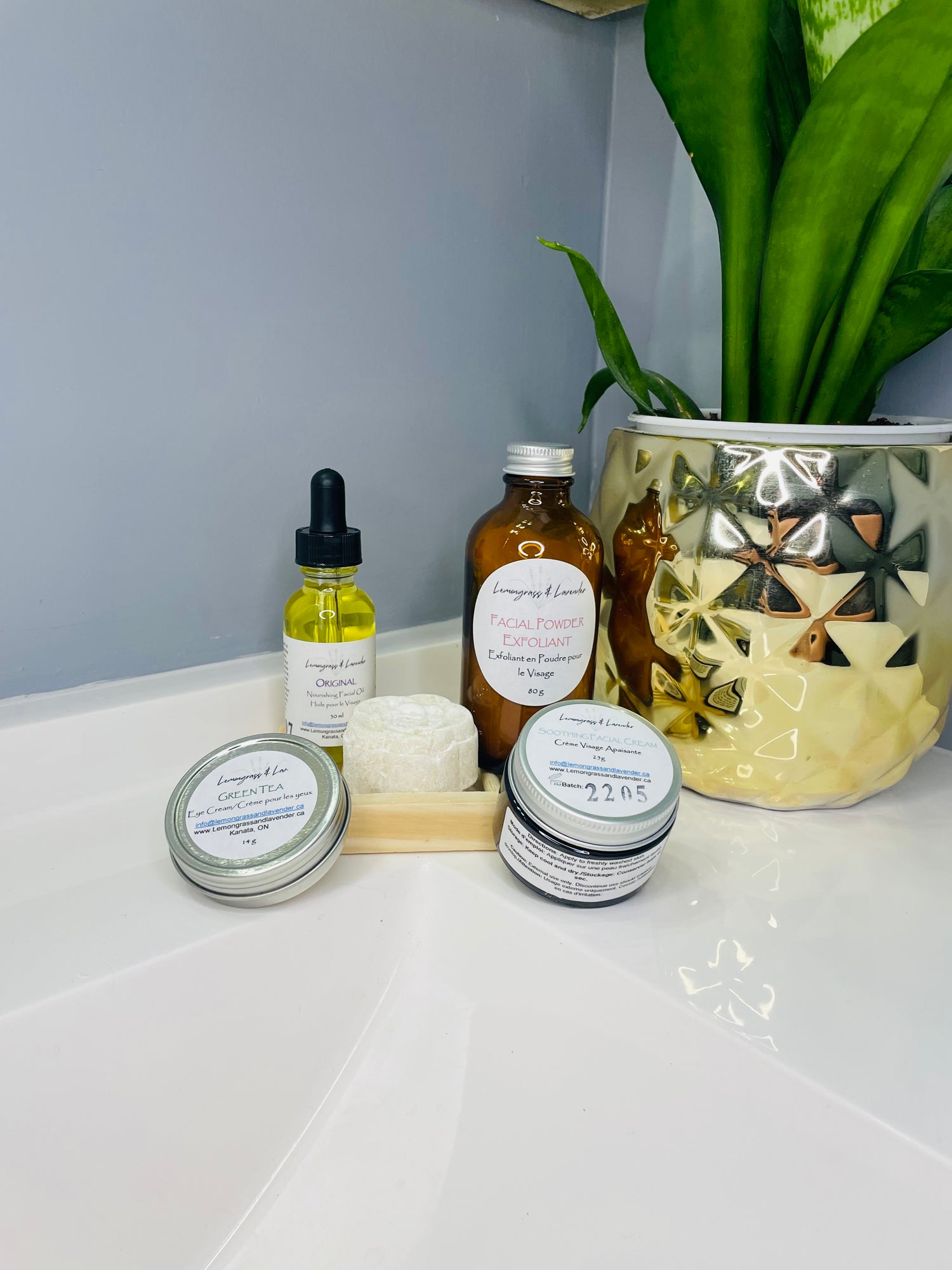 Image of Lemongrass & Lavender products on a bathroom vanity (products include: Nourishing Facial Oil - Original scent, Facial Powder Exfoliant, Facial Cleansing Bar, Green Tea Eye Cream, Soothing Facial Cream)